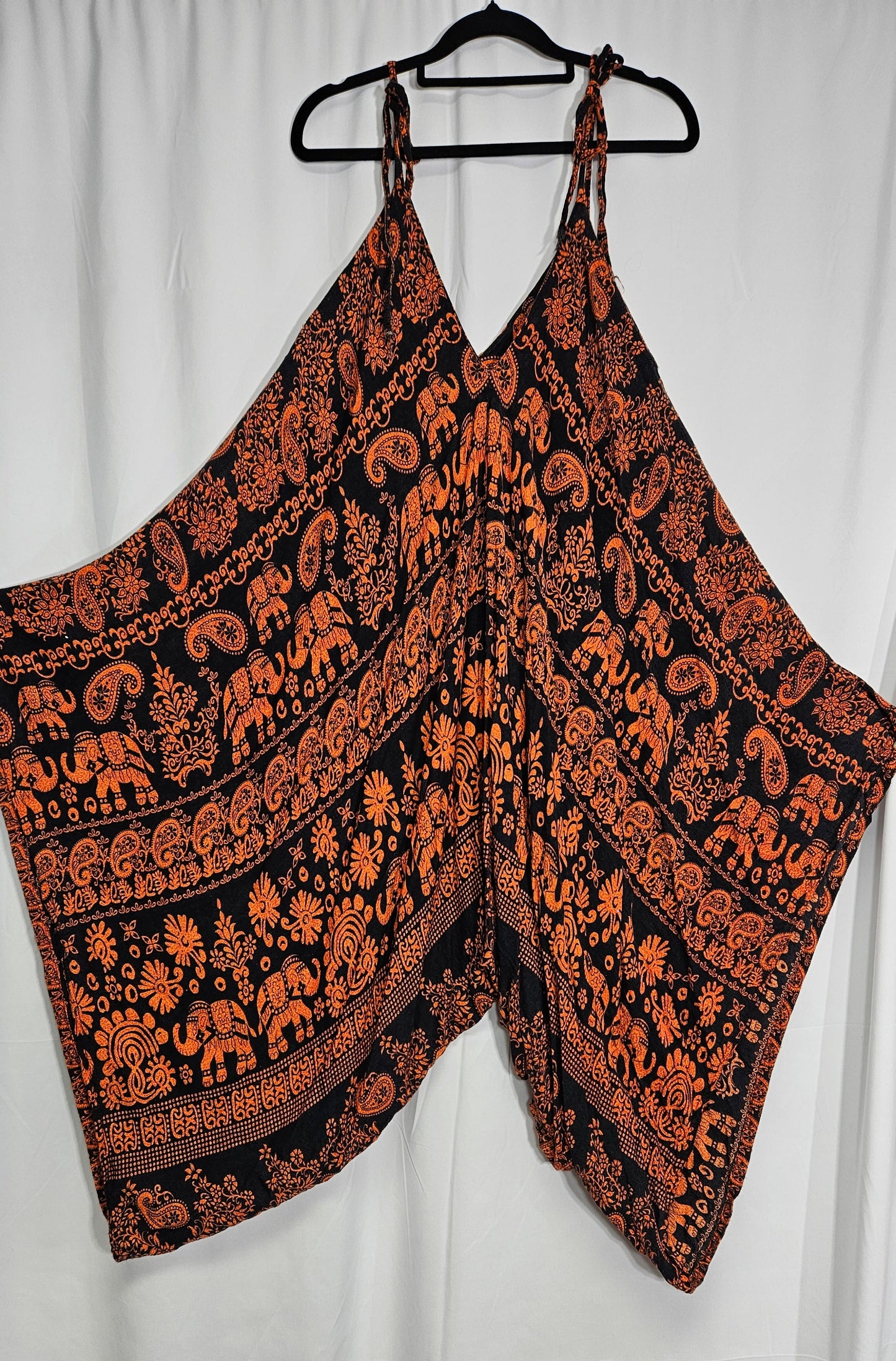 A hippie bohemian style jumpsuit with a balloon style silhouette, featuring a hippie pattern in muted colors. one size fits all. in good preloved condition