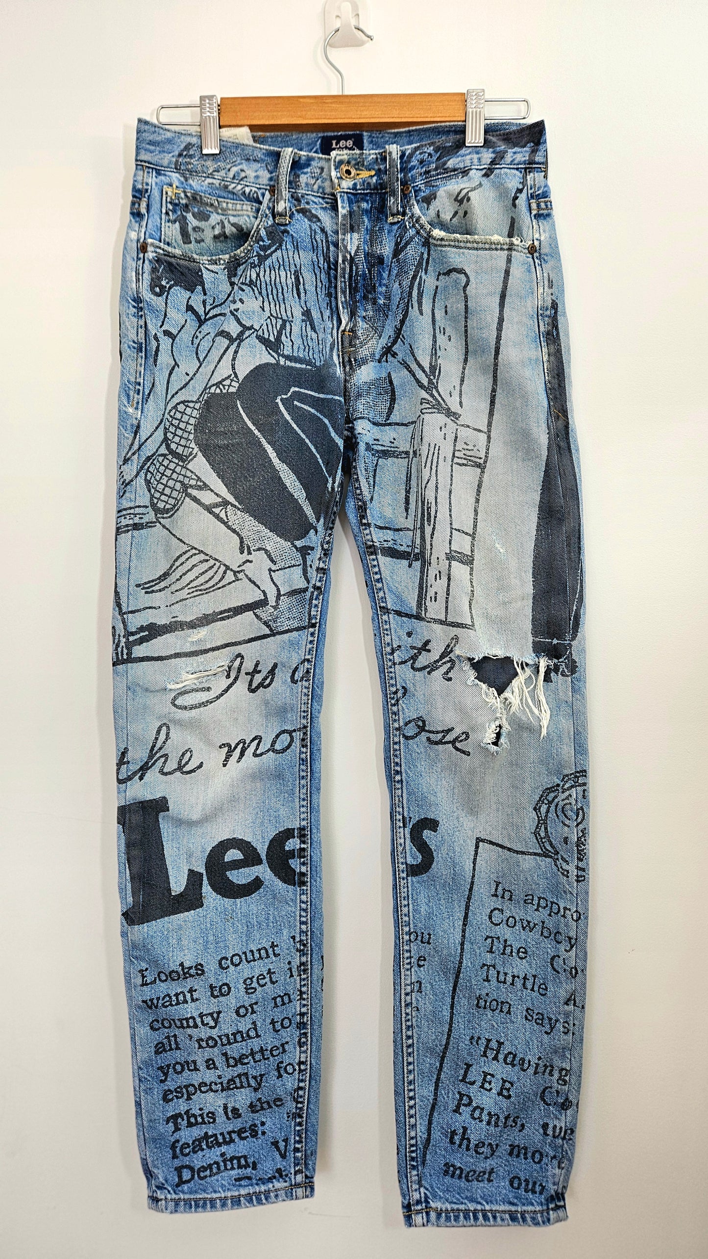 Lee 101+ straight-leg graphic jeans with black and white comic illustrations, cowboy artwork and faded yellow-toned denim, size W28 L29.