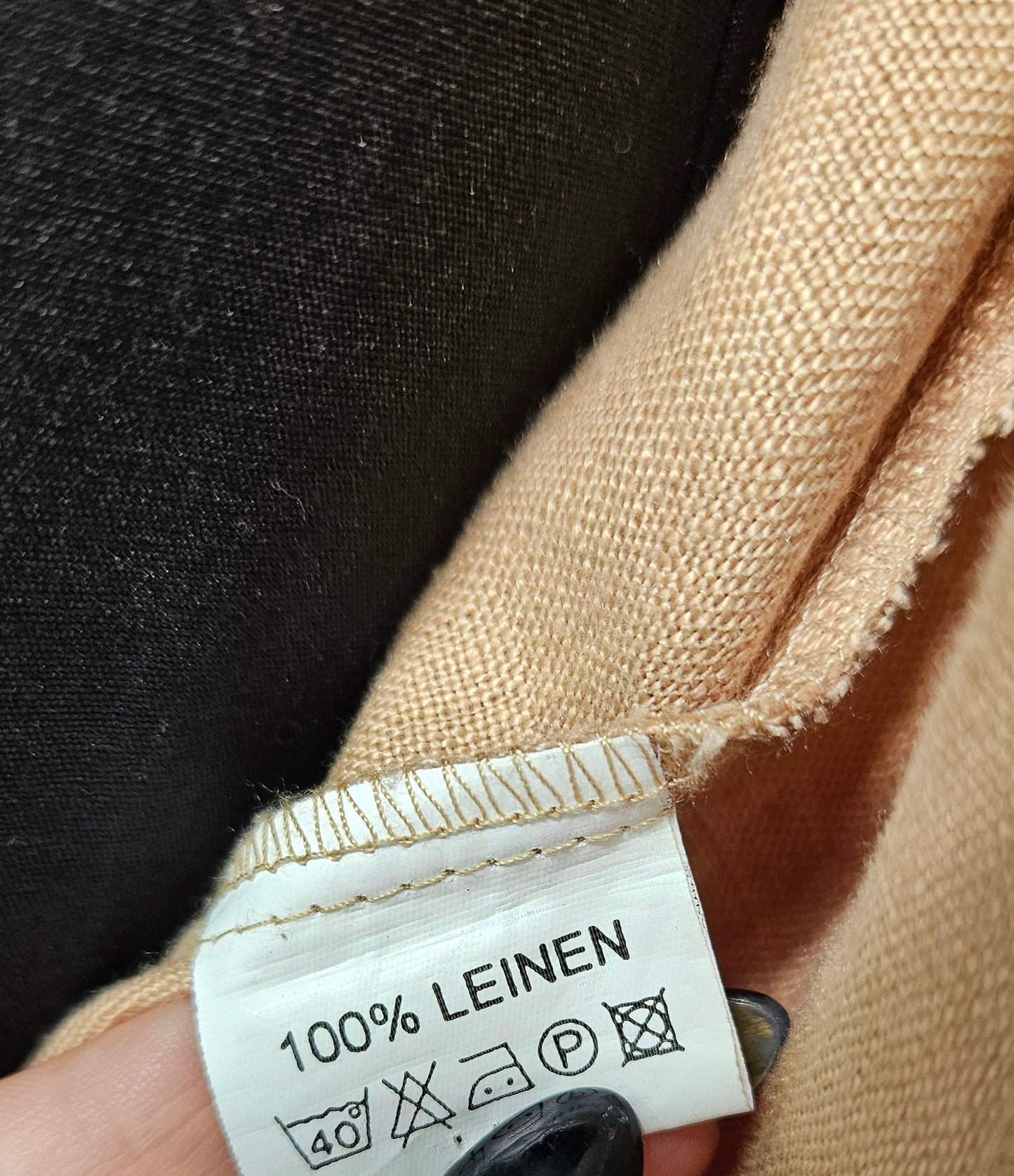 Close-up of a beige fabric with a label indicating 100% linen, preloved shirt
