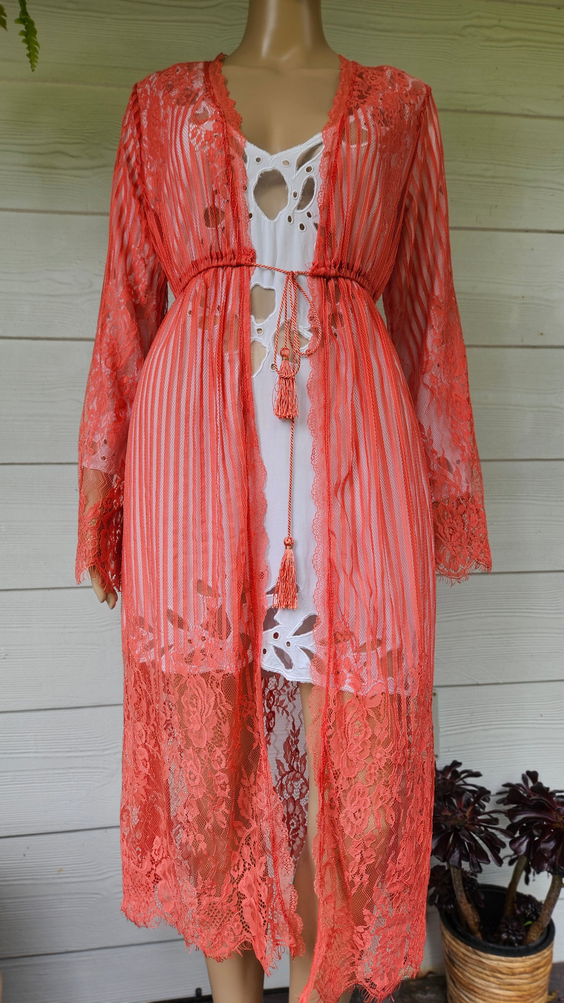 Coral lace dress on a mannequin against a light wooden floor background